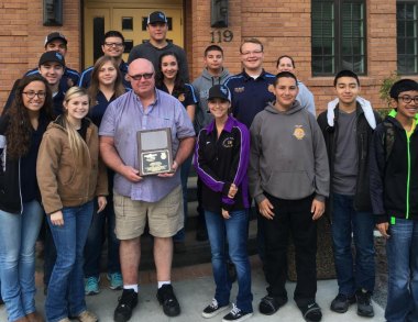 Ron King, (center) a former LHS ag instructor, accepts a plaque from the city and students for his work on the city hall landscaping project.